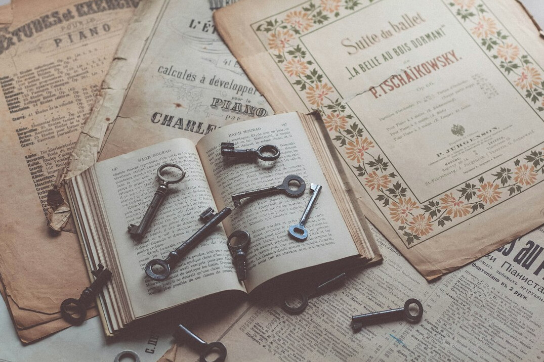 Open book with a vintage key and magnifying glass on top