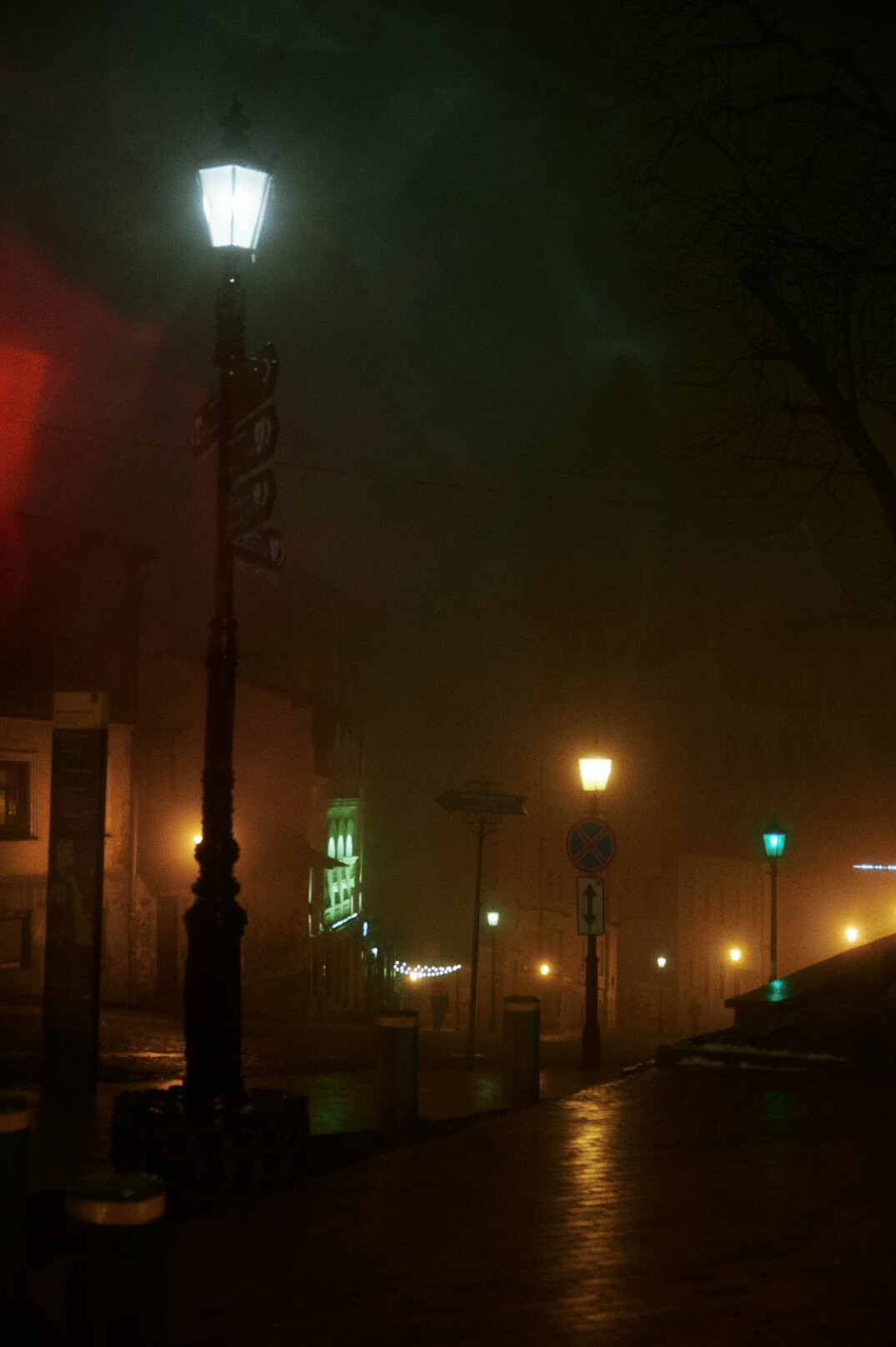 Foggy old European cobblestone street at night with a single lamp post